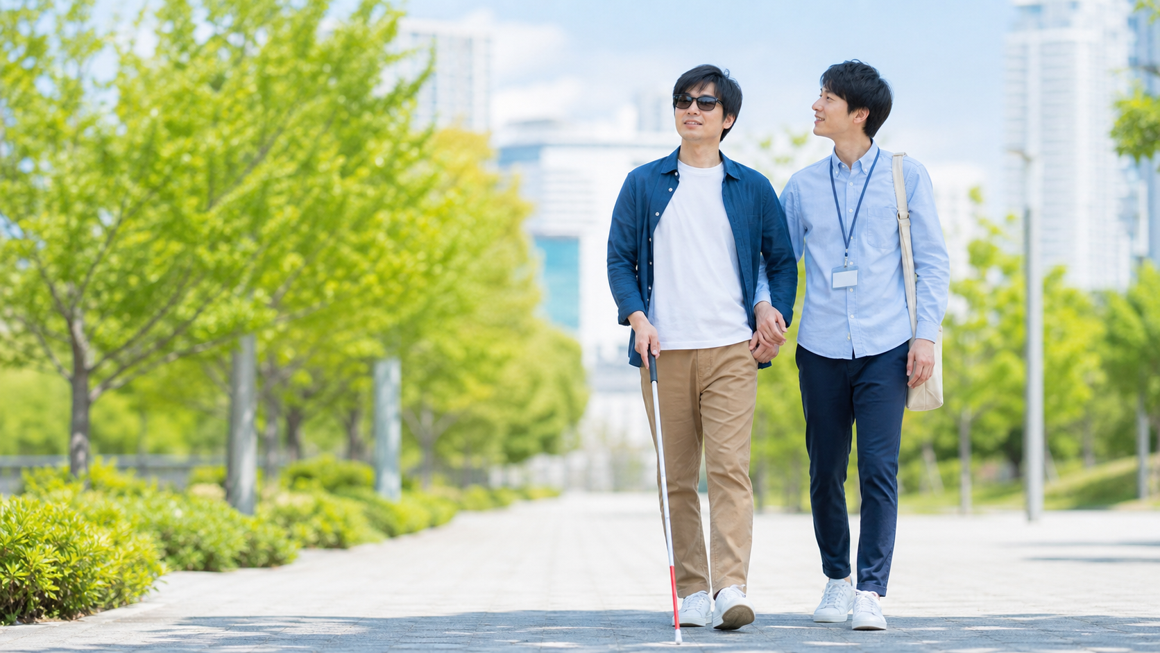 白杖を持つ人とガイドヘルパーが明るい屋外を歩くイメージ